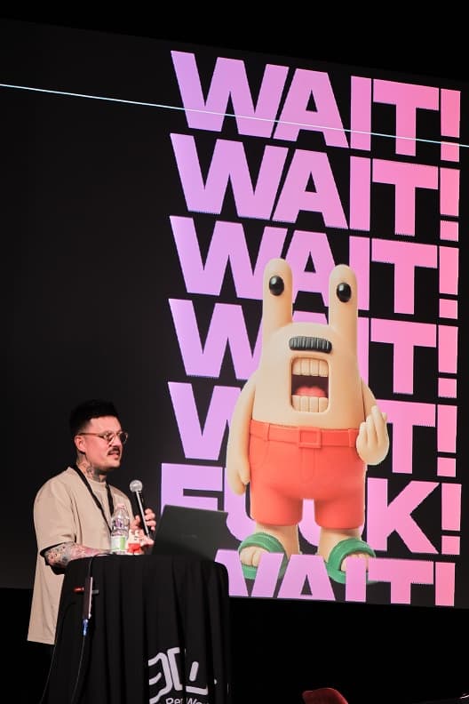 A speaker on stage in front of a large projected artwork
