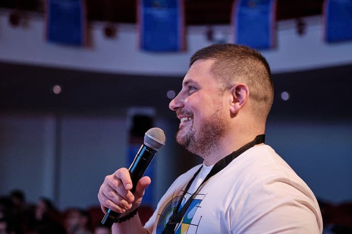 A speaker addressing the audience, microphone in hand